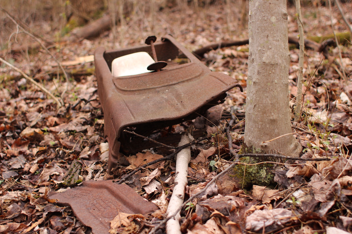 The rusting remnants of a child's pedal car sit in the middle of nowhere